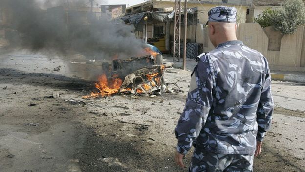 un soldat irakien face à la carcasse d'une voiture piégée à Kirkouk
