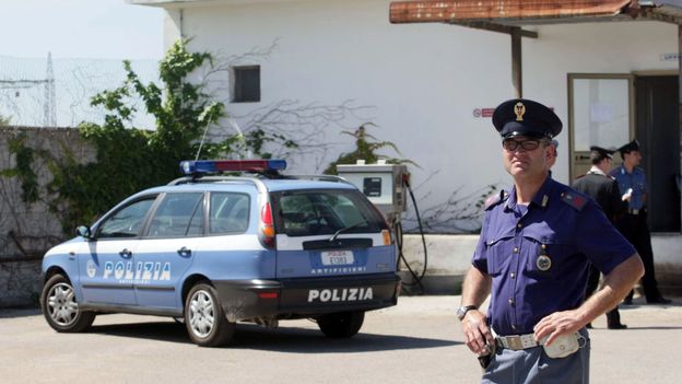 Des policiers devant le suspect de l'attentat de Brindisi