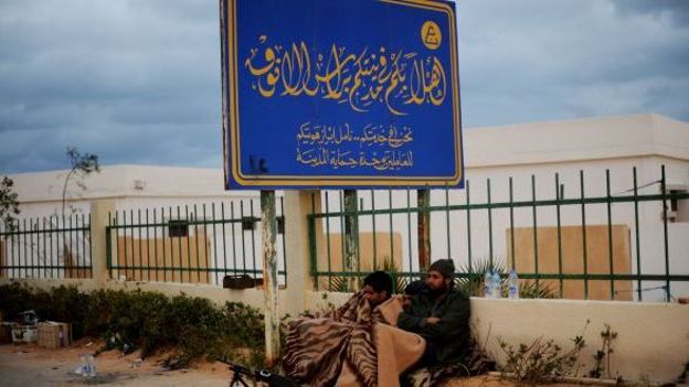 Combattants libyens sous un panneau annonçant la bienvenue en Libye