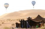 Des femmes touaregs photographient des montgolfières avec leur GSM dans le désert près de Ghadamès