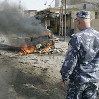 un soldat irakien face à la carcasse d'une voiture piégée à Kirkouk